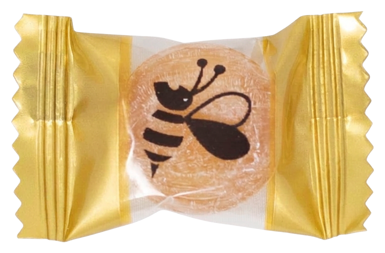 A single MGO Manuka Honey lozenge in its own gold wrapper printed with a bee